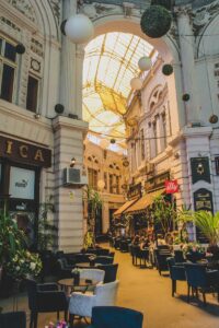 Arcade européenne avec sièges de café, mettant en valeur l'élégance architecturale et l'atmosphère animée.