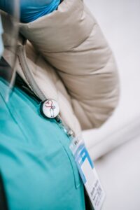 Femme méconnaissable portant un uniforme médical et un manteau avec un badge sur la poitrine attaché avec un signe rond avec un cœur et un stéthoscope