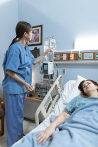 Une infirmière s'occupe d'un patient dans une chambre d'hôpital, s'assurant que l'équipement médical fonctionne.
