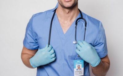 Médecin positif en uniforme bleu et gants de protection debout avec un stéthoscope et regardant la caméra sur fond clair