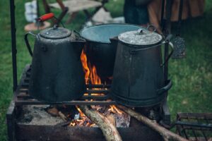Bouilloires et marmites de camping sur un feu ouvert dans un camping en plein air, idéales pour les thèmes de cuisine rustique.